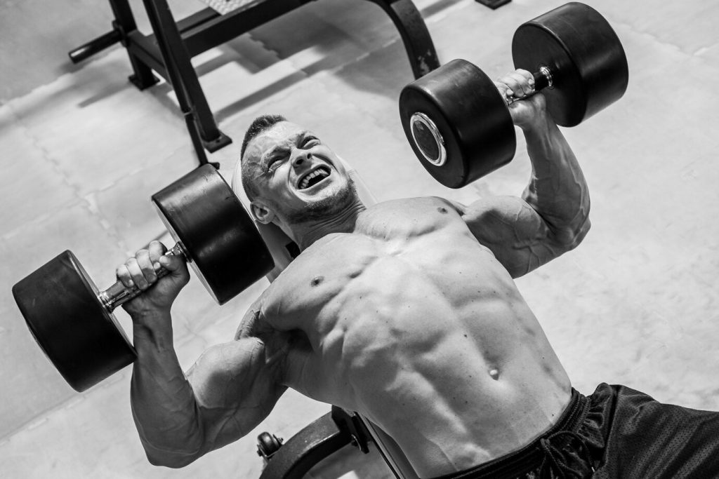 Man lifting heavy weights with growth hormone therapy benefits