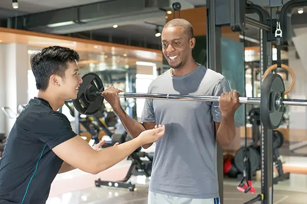 Man lifting barbell with personal trainer