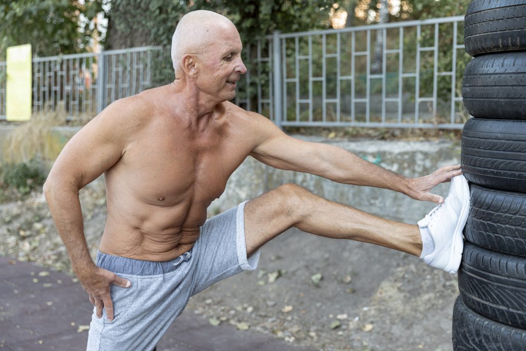 muscular elder man stretching outdoors with testosterone at PracticeRx